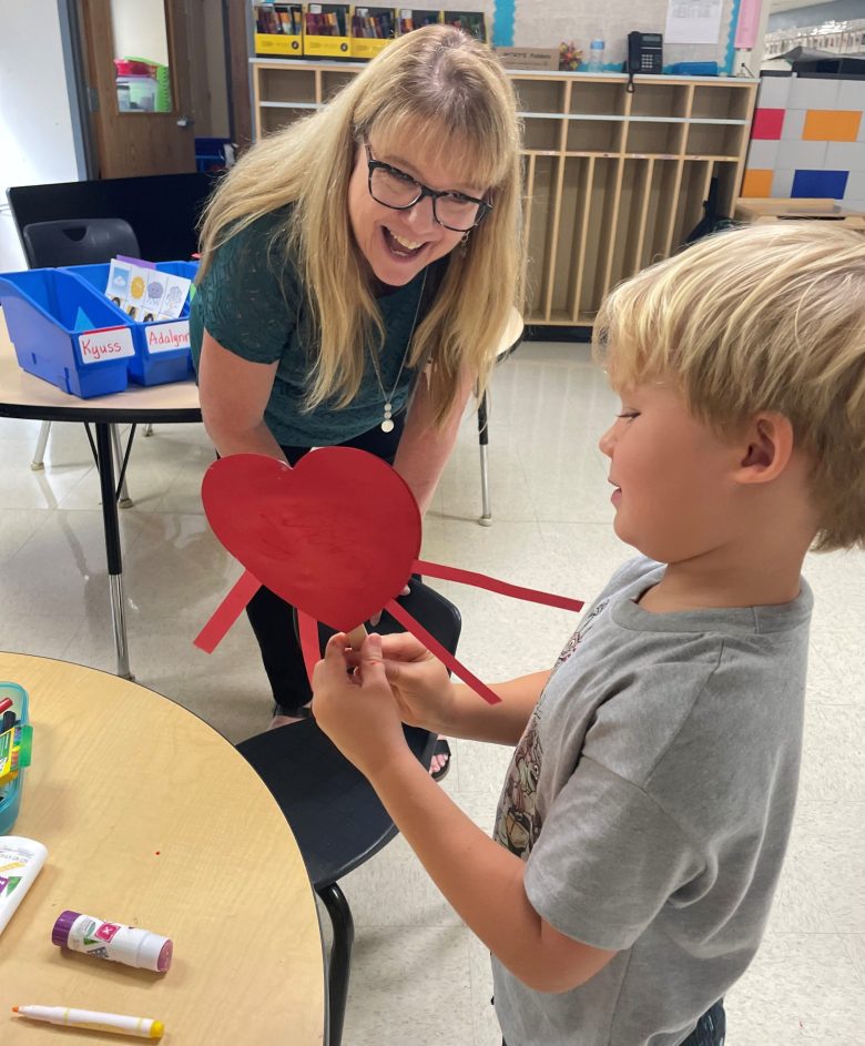 Boy Showing Heart Craft to Teacher